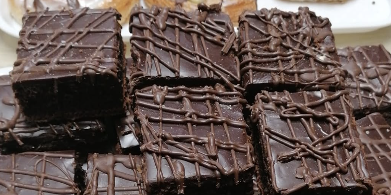Famous chocolate squares from Ravens Bakery – rich, fudgy, and topped with a smooth chocolate layer, a must-try treat loved by Zoe Sugg and Alfie Deyes.