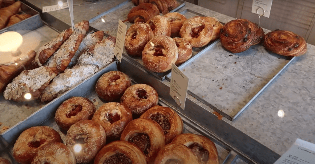 A glass display case at Coffee & Pastries in Lewes filled with golden-brown raspberry danishes, almond croissants, and flaky pain aux raisins.