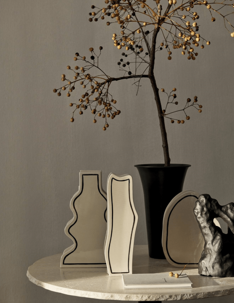 Ferm Living Paste Vase placed on a round table with other sculptural decor pieces.