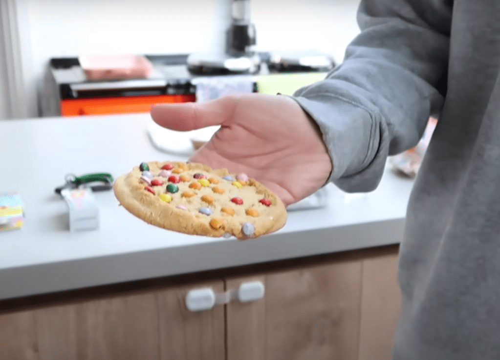 A large soft cookie covered in colorful candy-coated chocolate pieces.