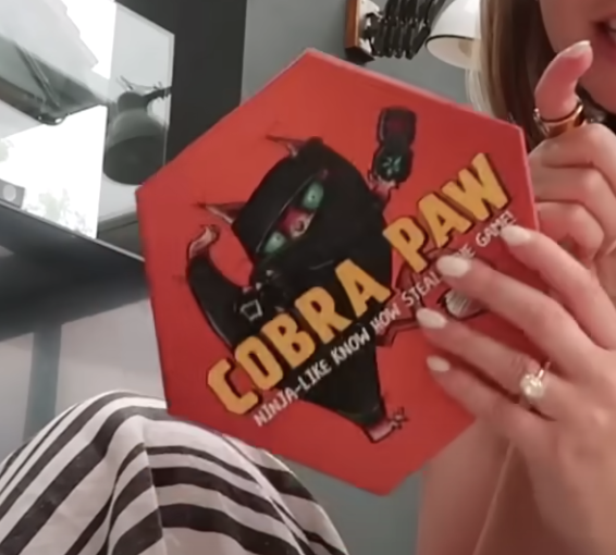 Zoe Sugg holding Cobra Paw board game while discussing it in her vlog.