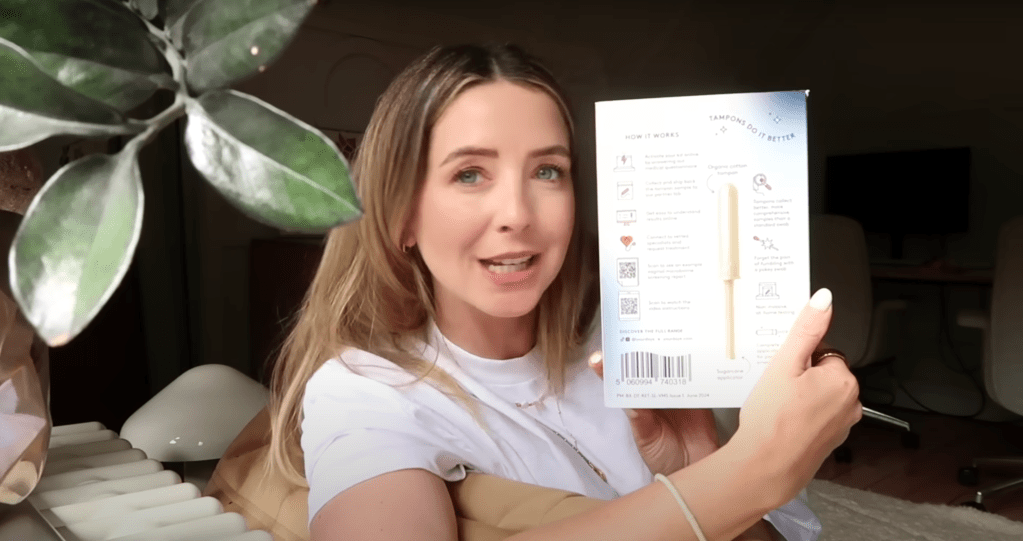 Zoe Sugg holding the back of the Daye diagnostic tampon box, pointing to instructions on how it works.