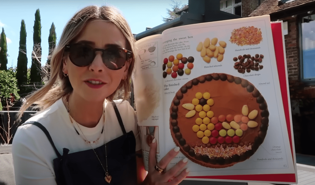 Zoe Sugg holds up a childhood cookbook by Rena Coyle that features beginner-friendly baking recipes. 📝
