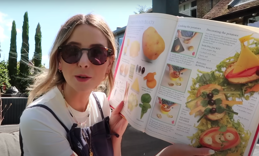 Zoe Sugg holds open a cookbook featuring a recipe for Cheesy Potato Boats.