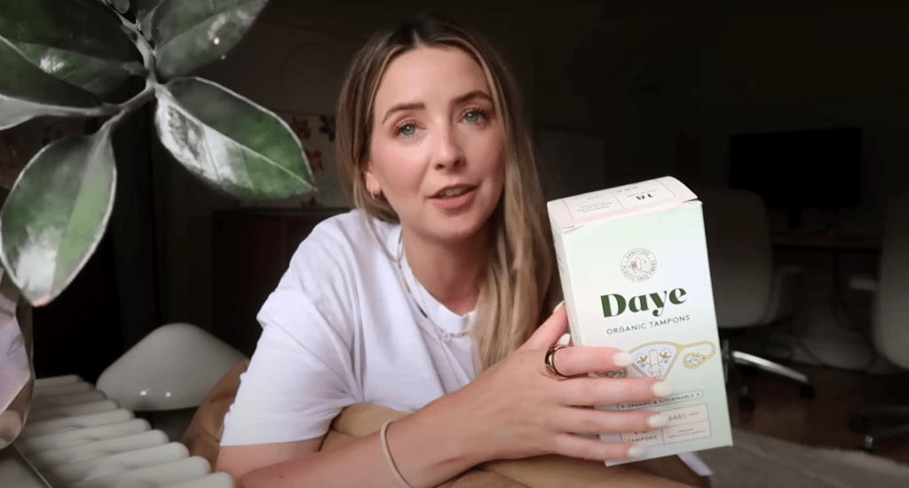 Zoe Sugg holding a yellow Daye tampon box, talking about its benefits.